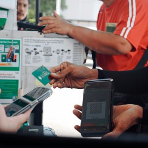 Customer paying with smartphone and credit card at checkout.