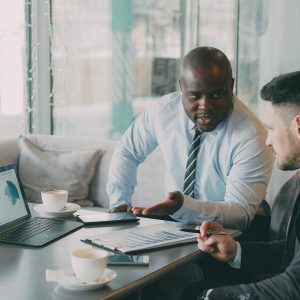 Two businessmen discussing charts on a laptop.