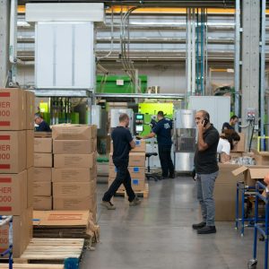 man in gray shirt standing beside brown cardboard boxes